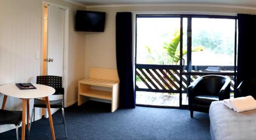 a room with a white couch and a white refrigerator, Kerikeri Holiday Park & Motels in Kerikeri