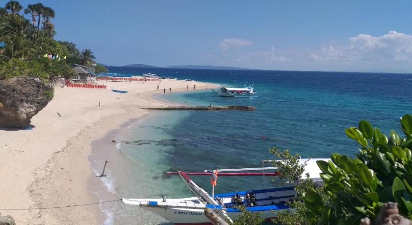 a beach with two boats parked on the beach, Edgewater Dive & Spa Resort in Puerto Galera