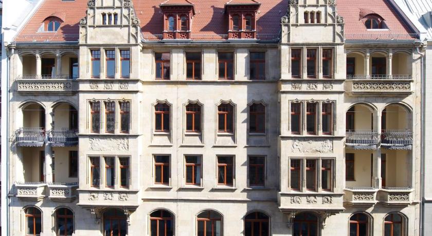 a large brick building with a clock on the front of it, Apartmenthotel Quartier M in Leipzig