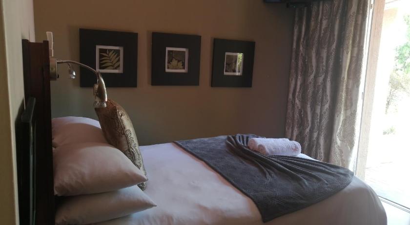 a bed with a pillow and a blanket on top of it, Aalwyns Guesthouse in Vanderbijlpark