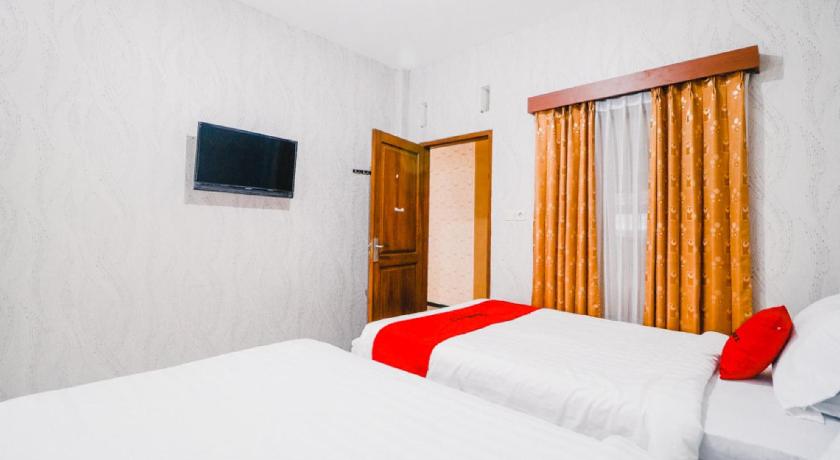 a hotel room with a bed and a television, RedDoorz near Taman Rekreasi Selecta in Malang