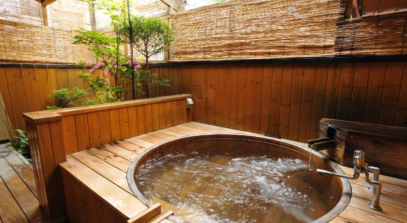 a bath tub sitting next to a pool of water, Shibu Onsen Kokuya in Nagano
