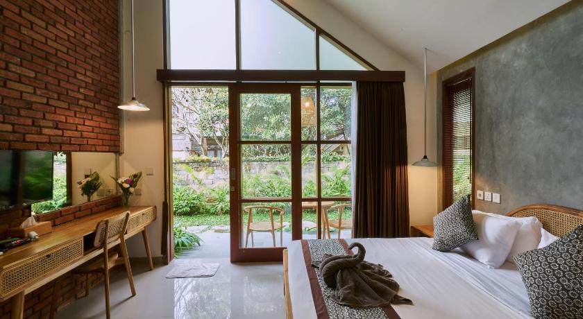 a room with a bed, a chair and a window, Yarama Cottages in Bali
