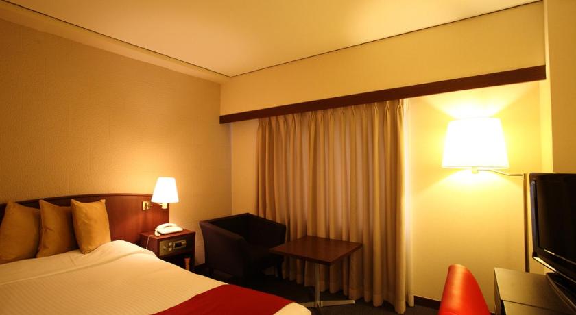 a hotel room with a bed and a television, Konaya Hotel in Kofu