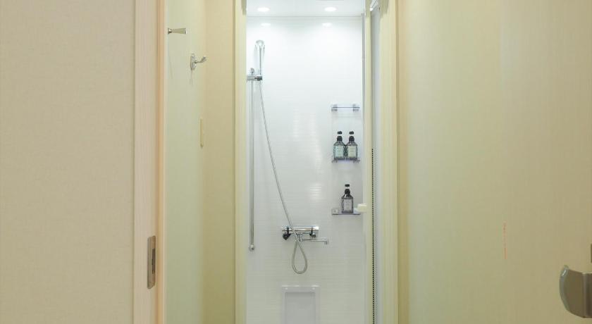 a bathroom with a door open and a shower stall, Leo Yu Capsule Hotel Funabashi in Funabashi