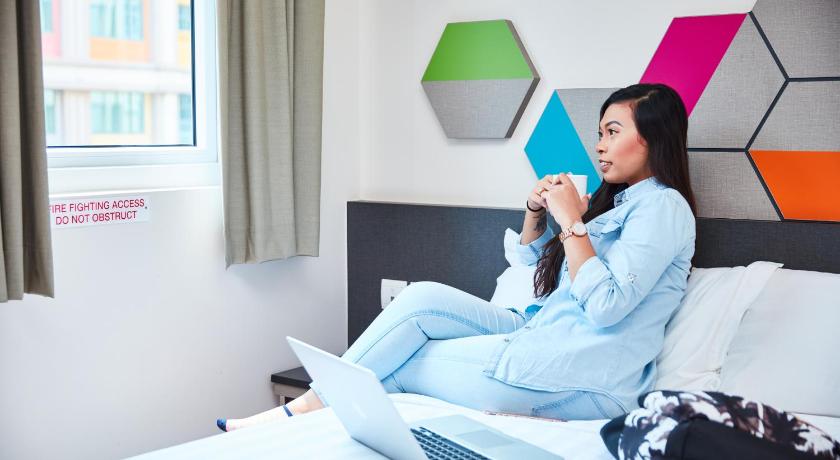 a person sitting on a bed using a laptop, ibis budget Singapore Emerald (SG Clean Certified, Staycation Approved) in Singapore
