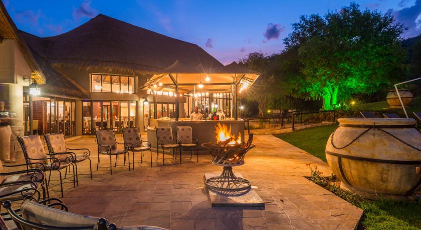 a patio with a table, chairs, and a fire place, Ivory Tree Game Lodge in Pilanesberg