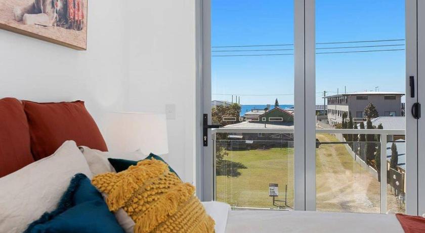 a bed sitting in front of a window in a hotel room, Silica Sands Beach House by Kingscliff Accommodation in Kingscliff