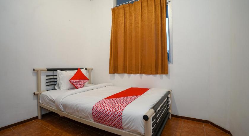 a bedroom with a bed and a lamp on the wall, Super OYO 1844 Bravo Residence in Bangka