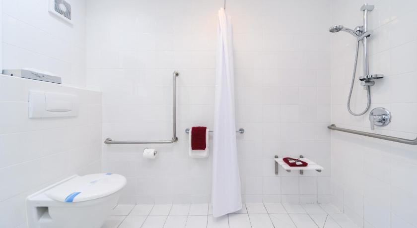a white toilet sitting next to a shower in a bathroom, Aubyn Court Spa Motel in Palmerston North