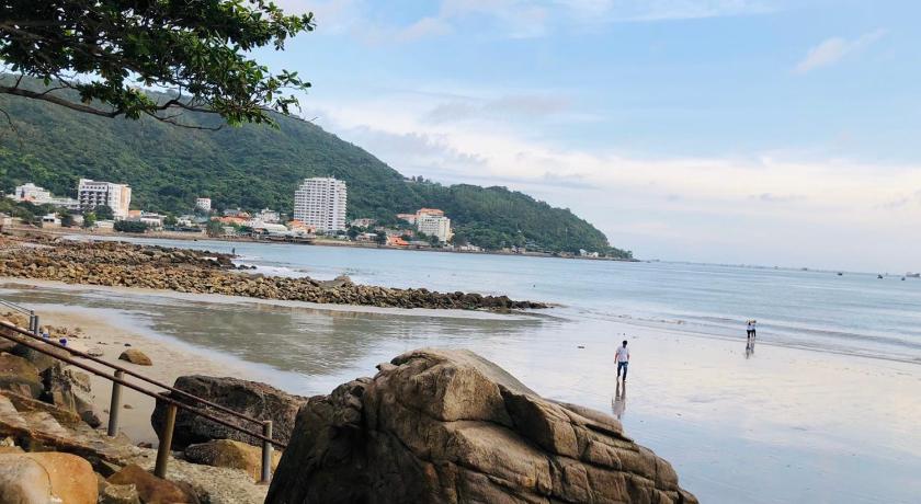 a person standing on a beach next to a body of water, MERMAID SEASIDE HOTEL in Vung Tau