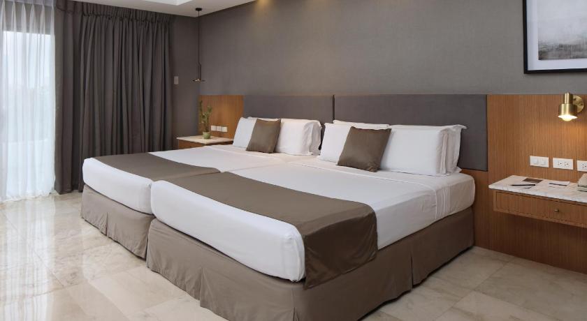a hotel room with a large bed and a large window, City Garden Suites Hotel in Manila