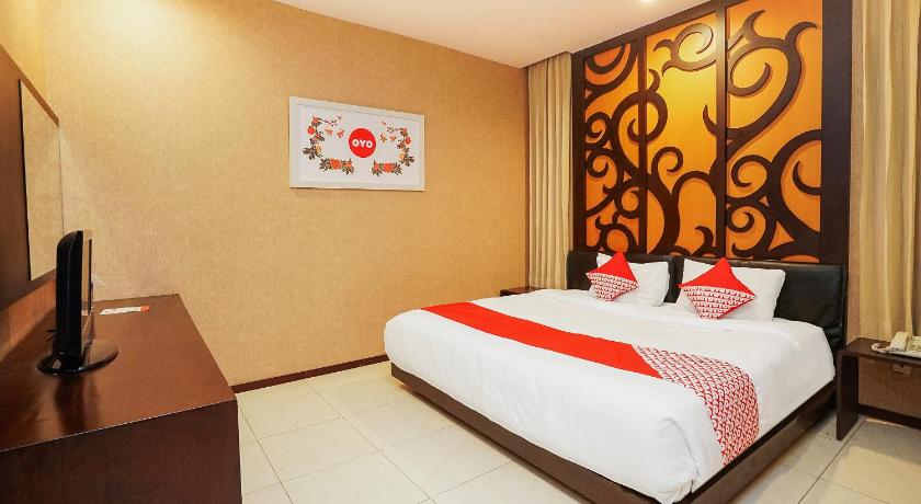 a hotel room with a large bed and a painting on the wall, OYO 252 Istana Permata Ngagel in Surabaya