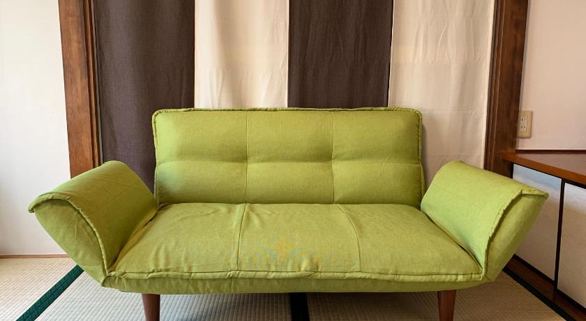 a green couch sitting on top of a wooden floor, Kamata Ann in Tokyo