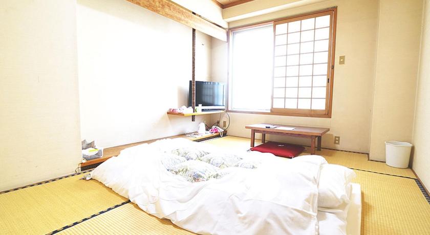 a bedroom with a bed and a television, Numaguchi Ryokan in Takanabe
