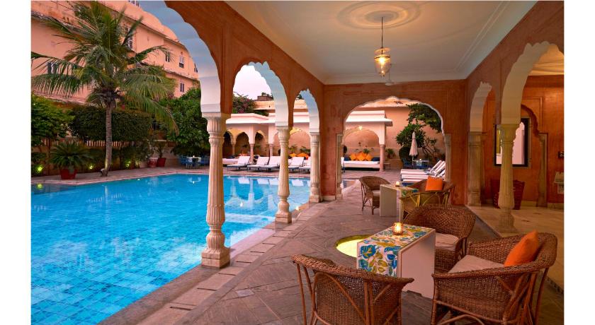 a room with a pool, chairs, and a table, Samode Haveli Hotel in Jaipur