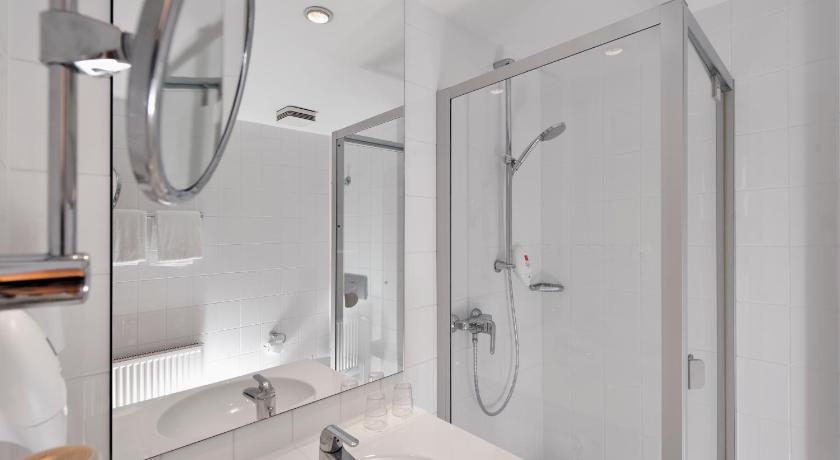 a bathroom with a shower, sink, and mirror, Wyndham Garden Potsdam in Potsdam