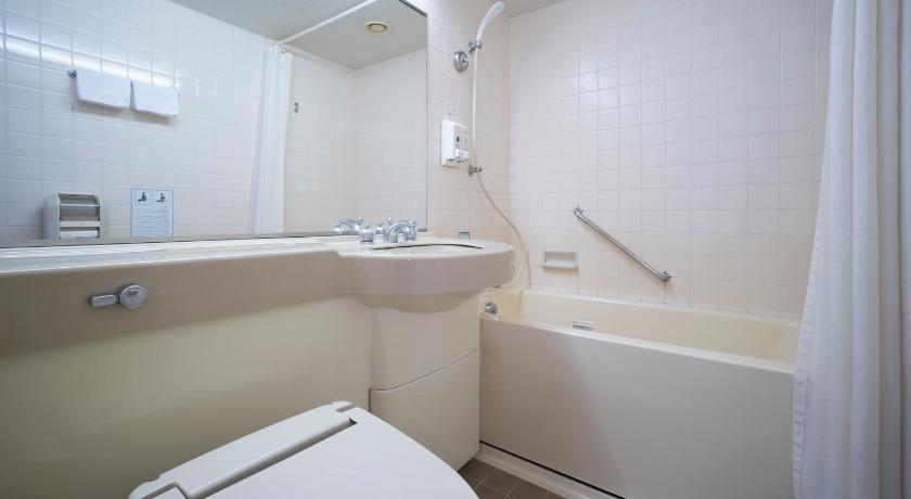 a white toilet sitting next to a bath tub in a bathroom, Kuwana Green Hotel in Yokkaichi