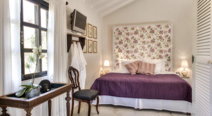 a bedroom with a bed, chair, and window, Villa Balthazar in Buzios