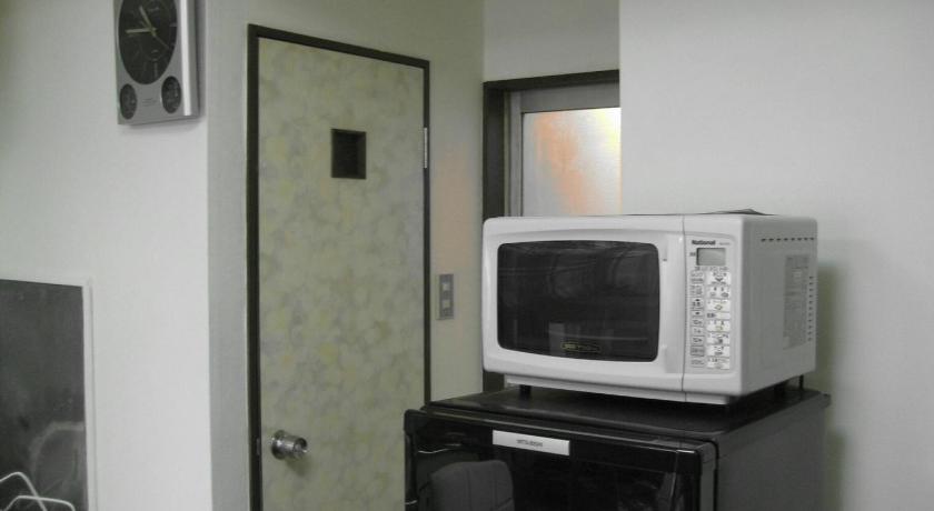 a microwave sitting on top of a wooden cabinet, Convenient Apartment in Otsuka in Tokyo
