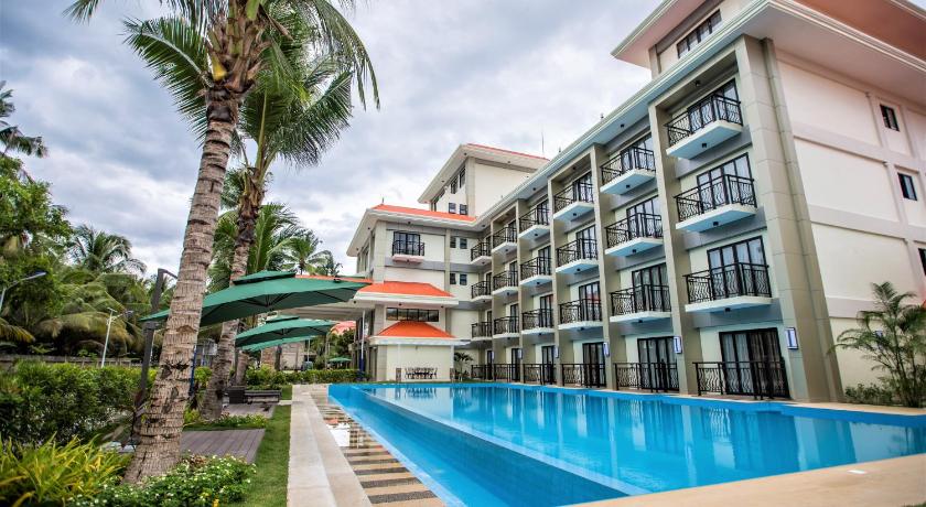 a large swimming pool in front of a large building, Costa Palawan Resort in Palawan