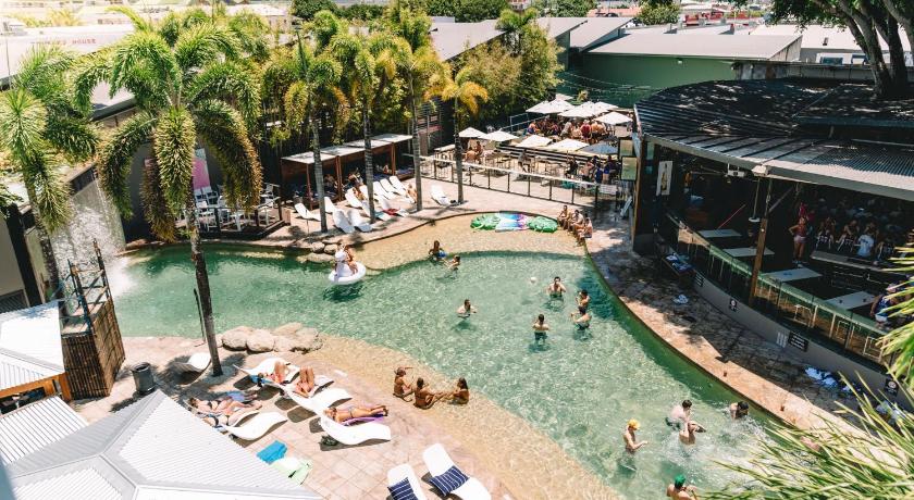 a large pool of water with several tables and umbrellas, Gilligan's Backpacker Hostel in Cairns