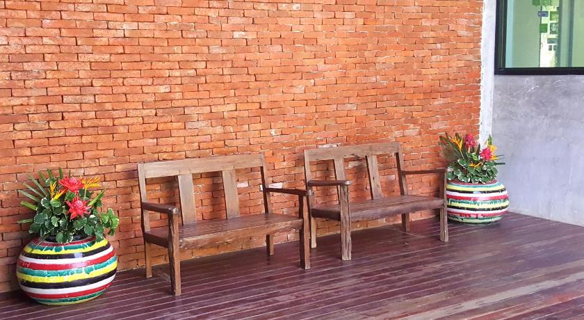 a row of wooden benches in front of a brick wall, Tropicana Lanta Resort in Koh Lanta