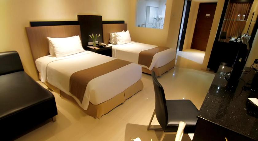 a hotel room with two beds and a desk, Aria Gajayana Hotel in Malang