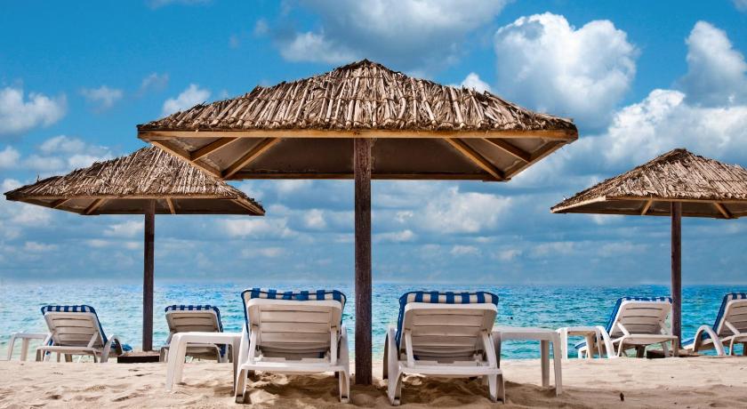 a beach area with chairs and umbrellas, Ramada Hotel & Suites by Wyndham Ajman in Ajman