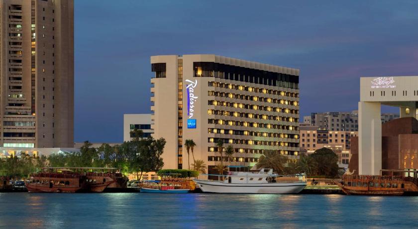 a large white boat floating on top of a body of water, Radisson Blu Hotel Dubai Deira Creek in Dubai