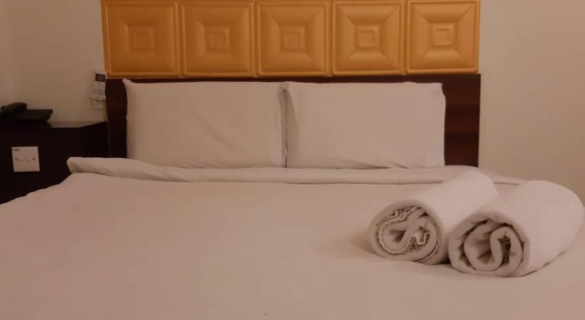 a white bed with a white pillow on top of it, Hotel Bintang Indah in Kota Bharu