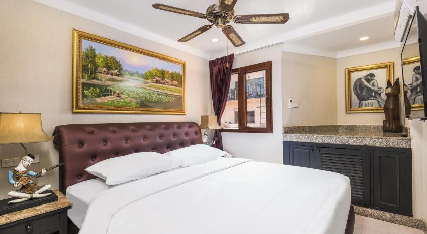 a hotel room with a large bed and a painting on the wall, Ambiance Pattaya Hotel in Pattaya