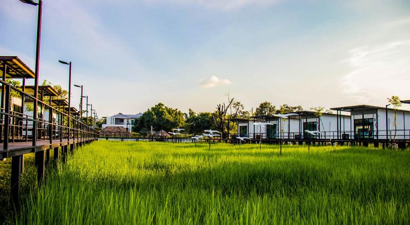 a field full of green grass with a train on the tracks, Mae On Village Resort in Roi Et