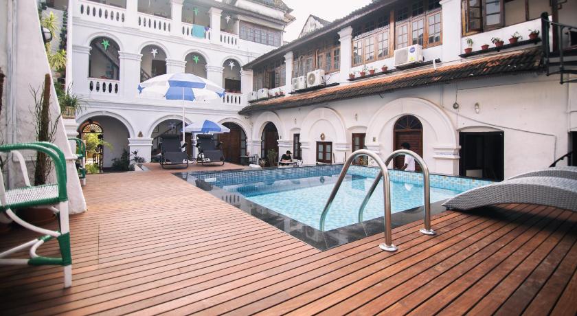 a swimming pool with two chairs and a balcony, Old Courtyard Hotel in Kochi