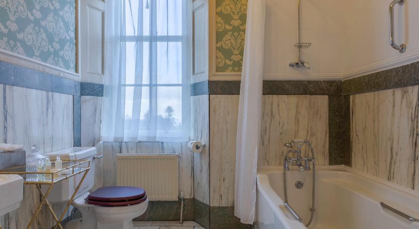 a white toilet sitting next to a bath tub in a bathroom, Glenapp Castle in Ballantrae