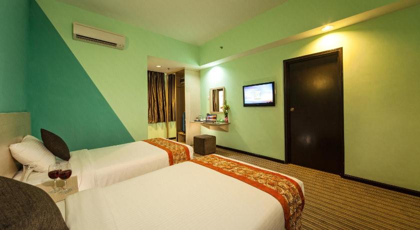 a hotel room with two beds and a television, Thy Executive Hotel in Johor Bahru