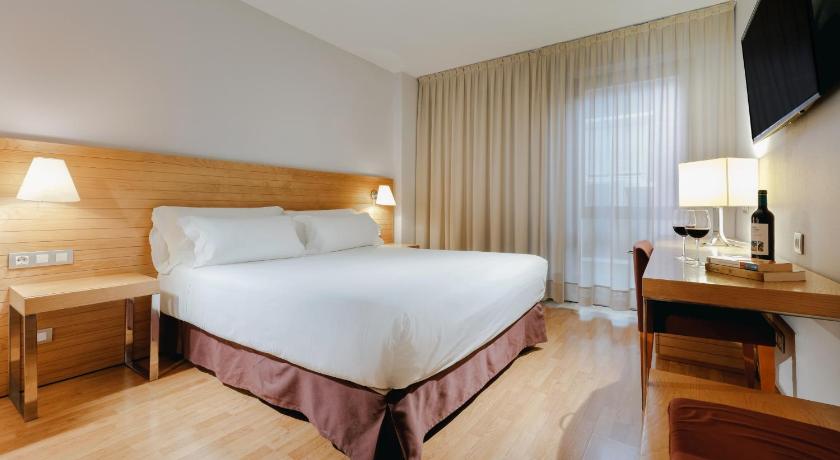 a hotel room with a bed, desk, chair and a lamp, Hesperia Zaragoza Centro in Zaragoza