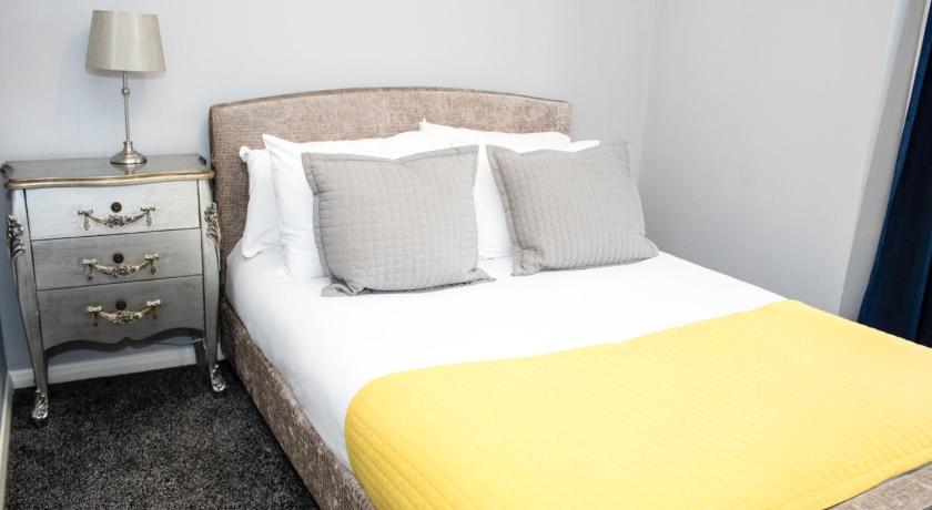 a white bed with a white comforter next to a lamp, Edinburgh Playhouse Apartments in Edinburgh