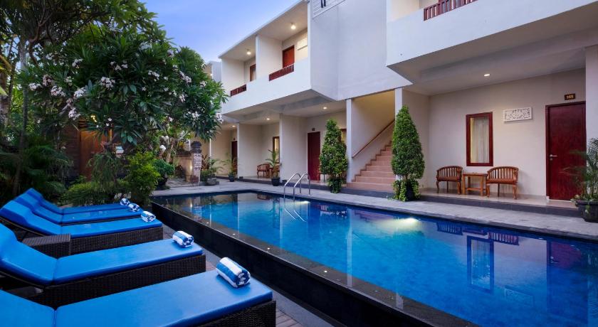 a swimming pool with blue chairs and blue umbrellas, Nesa Sanur Hotel in Bali