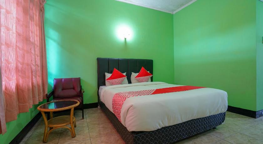 a bedroom with a bed, a chair, and a lamp, Super OYO 1389 Hotel Carissima in Palembang