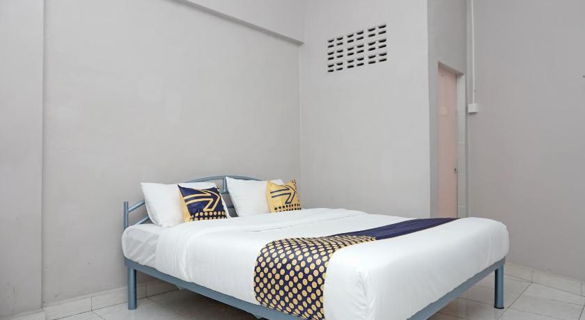 a bed in a room with a white bedspread, SPOT ON 2200 Hotel Gunung Sari in Rantauprapat