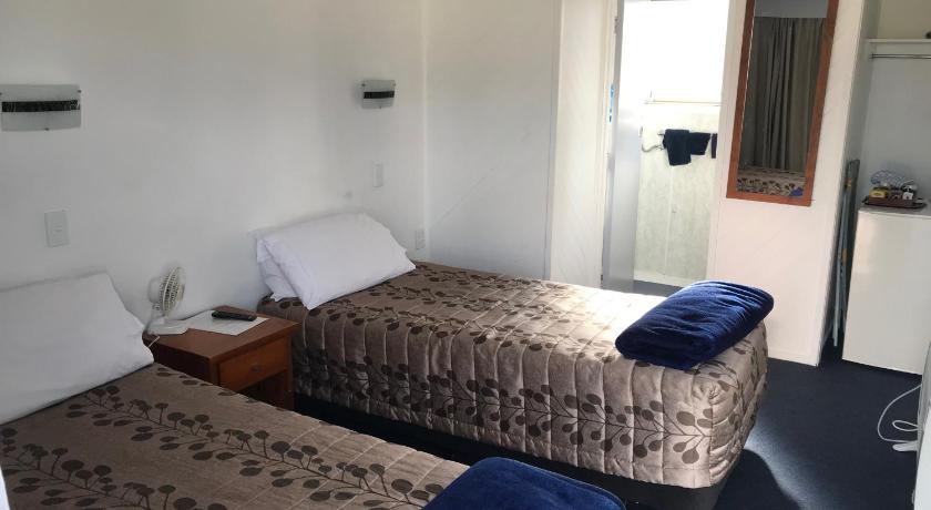 a hotel room with two beds and a television, Orana Motor Inn in Kaitaia