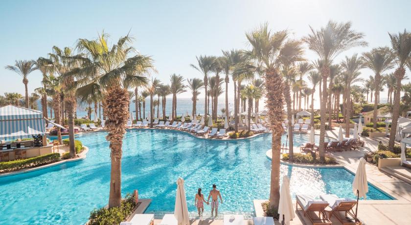 a beach scene with a pool, chairs, and tables, Four Seasons Resort Sharm El Sheikh Egypt in Sharm El Sheikh