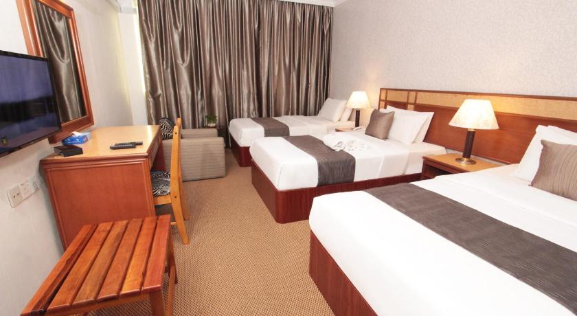 a hotel room with two beds and a television, Pelican Hotel in Batu Pahat