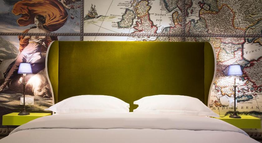 a bed with a white comforter and pillows on it, Du Continent Hotel in Paris