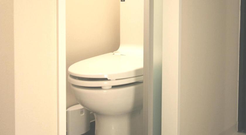a white toilet sitting next to a white wall, HOTEL MYSTAYS Shimizu in Shizuoka