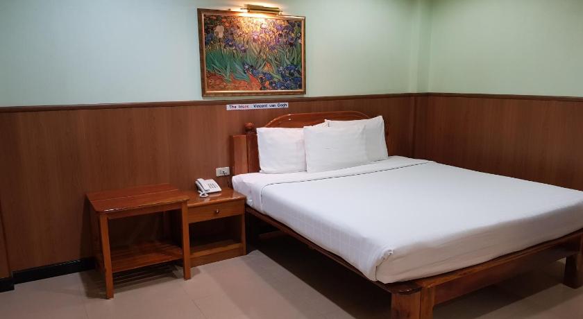 a bedroom with a bed, a desk and a lamp, Phadaeng Hotel in Ubon Ratchathani