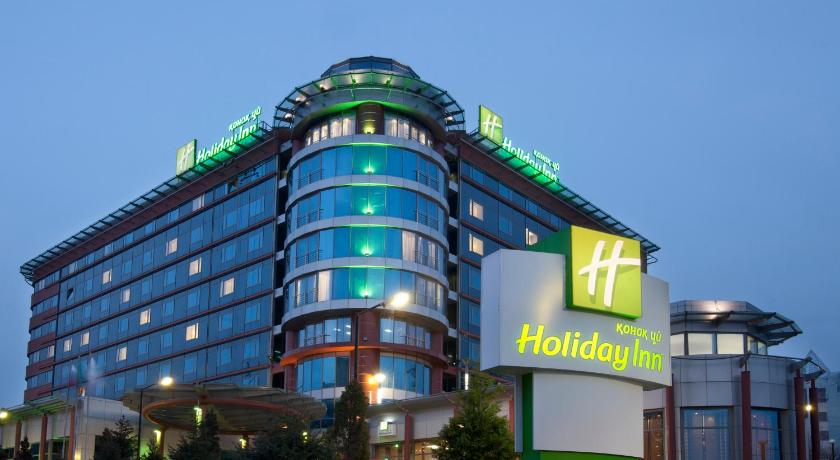 a large building with a large clock on the front of it, Holiday Inn Almaty in Almaty