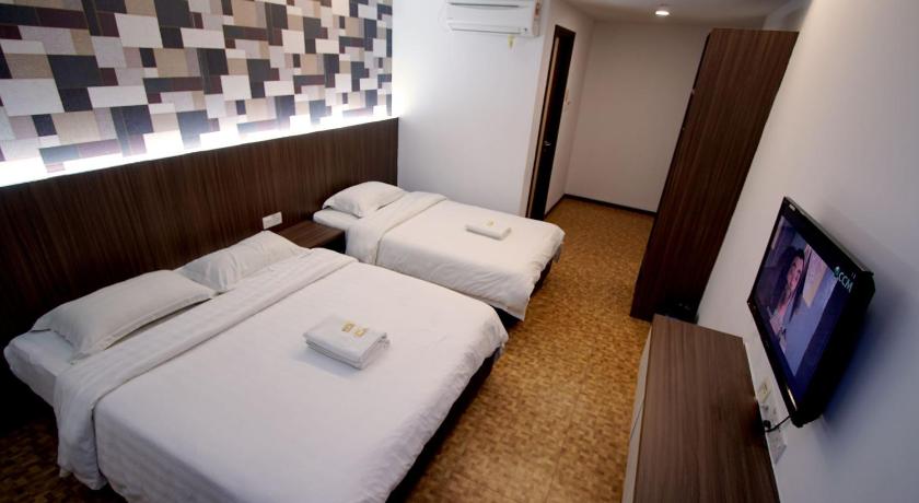 a hotel room with two beds and a television, Pavilion Inn in Miri