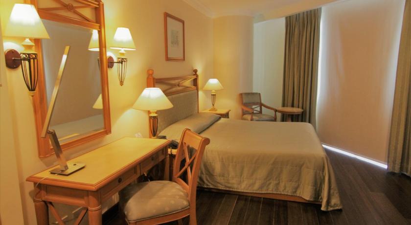 a hotel room with a bed, desk, chair and mirror, The Grand Dame Hotel in Iloilo